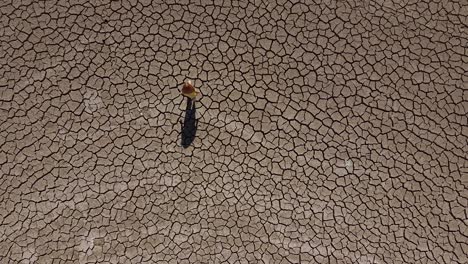 amplia vista aérea de una niña caminando sola a través de un paisaje seco y árido durante una sequía en chipre, grecia