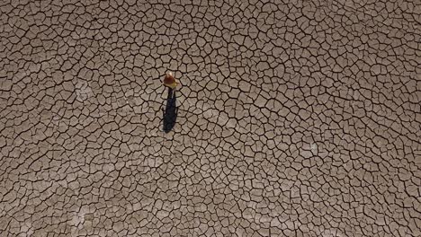 wide aerial view of a girl walking alone across a dry, barren landscape during a drought in cyprus, greece