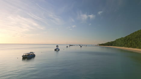 horizonte del atardecer, barcos flotando todavía, drones volando bajo playa natural isla de moreton, destino de viaje marítimo australiano