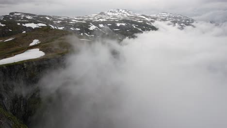 drone shot through clouds curling up the steep mountain sides in norway