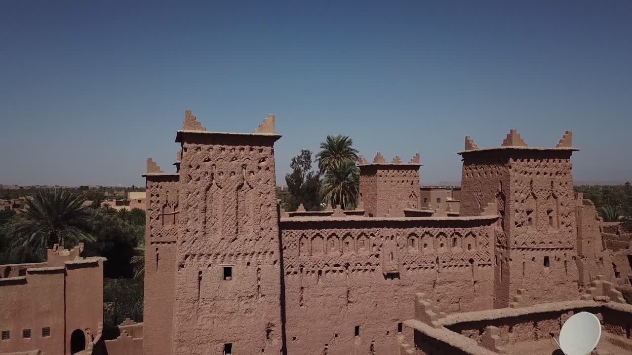 Primo piano aereo che si concentra sui tradizionali motivi geometrici berberi e sulle torri merlate della Kasbah di Taourirt. Il filmato mette in risalto la dettagliata lavorazione in mattoni di fango di questo storico Marocco