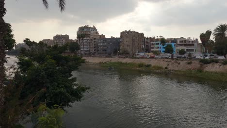 panorama view of nile river in cairo with residential buildings on the riverbank, cloudy sky