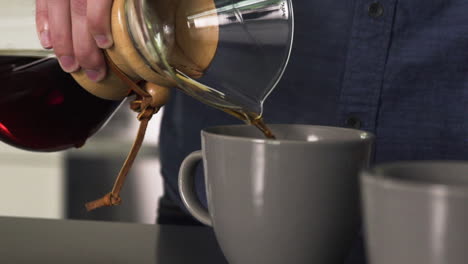 pouring fresh black coffee from a carafe into a coffee mug at home, slow motion