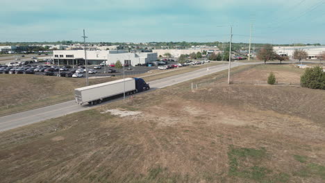 Truck driving on a road with cars dealership in the background