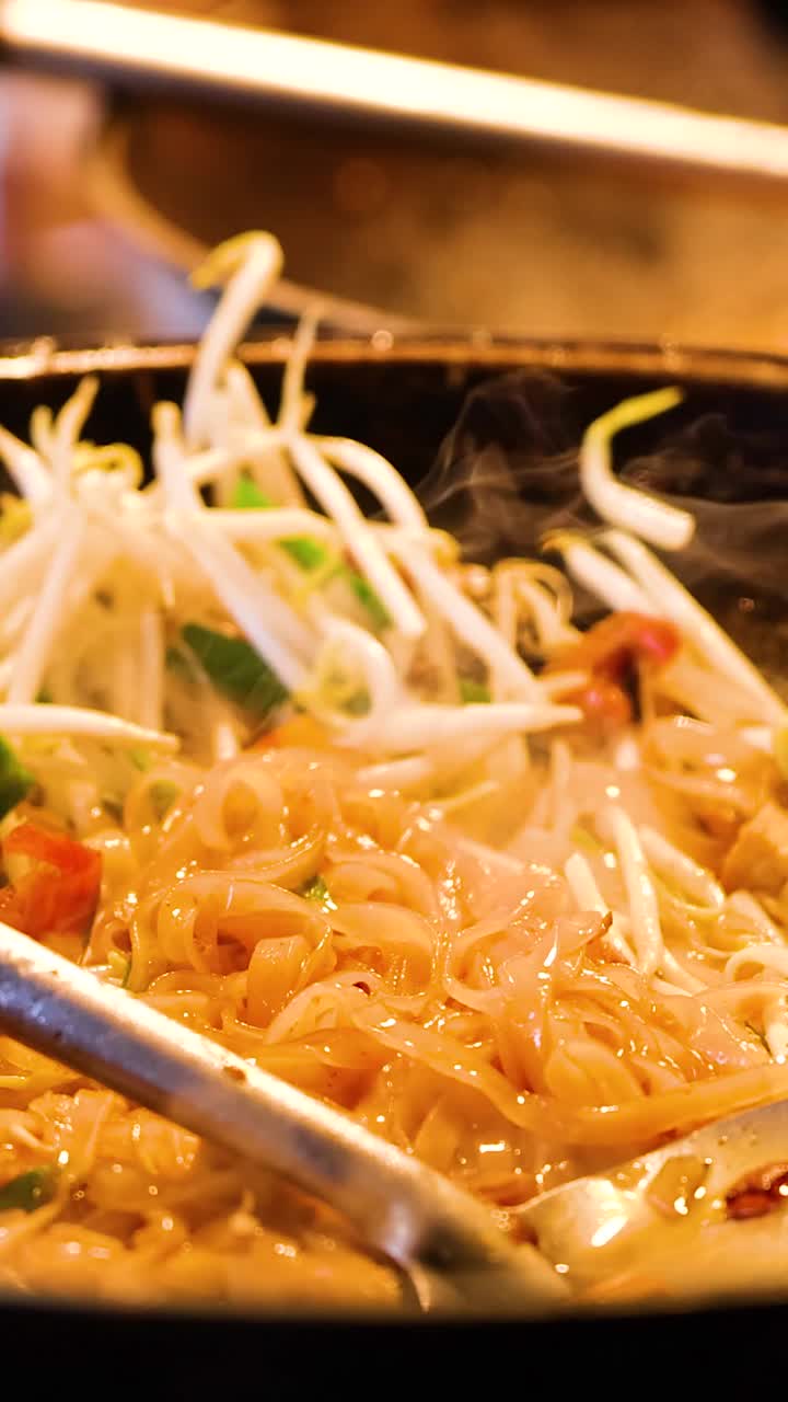 Stir-frying Pad Thai noodles in a hot wok