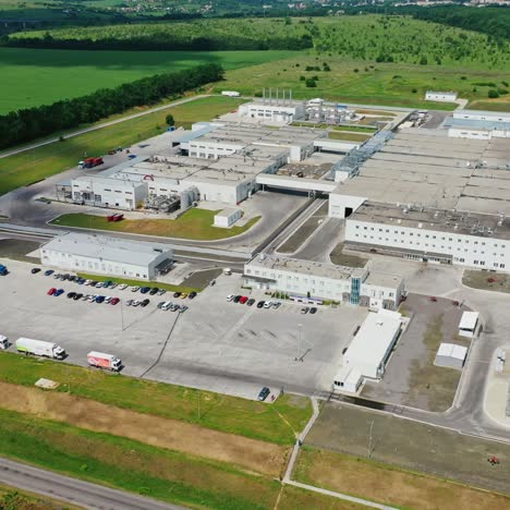 exterior of modern manufacturing in nature. large industrial complex with car parking among the environment in summer. motion top down.