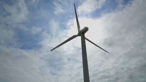 Wind-turbine-rotating-against-bright-cloudy-summer-sky