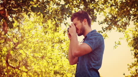 Handsome-man-using-retro-photo-camera-in-the-park