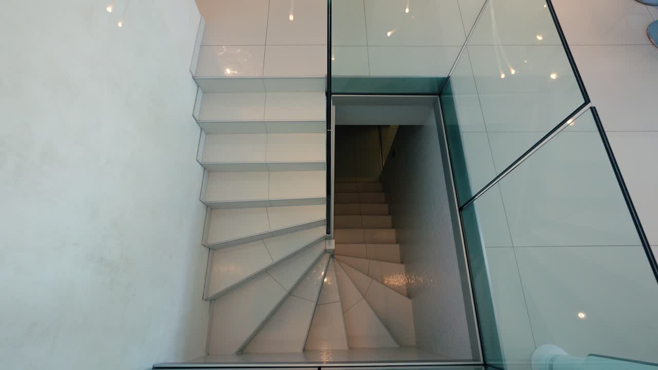 Slow descending shot of a marble staircase with glass partitions in a villa
