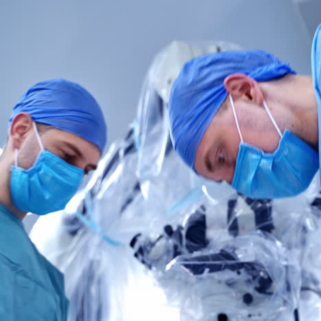closeup of two surgeons with operating microscope. health treatment concept.