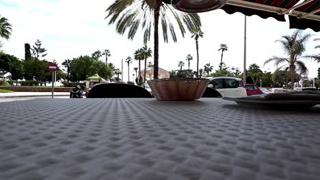 Low-angle-shot-on-the-table-of-a-restaurant-while-a-cool-and-freshly-tapped-beer-is-put-down-overlooking-the-busy-street-and-palm-trees-in-malaga-spain-on-the-way-through-on-vacation