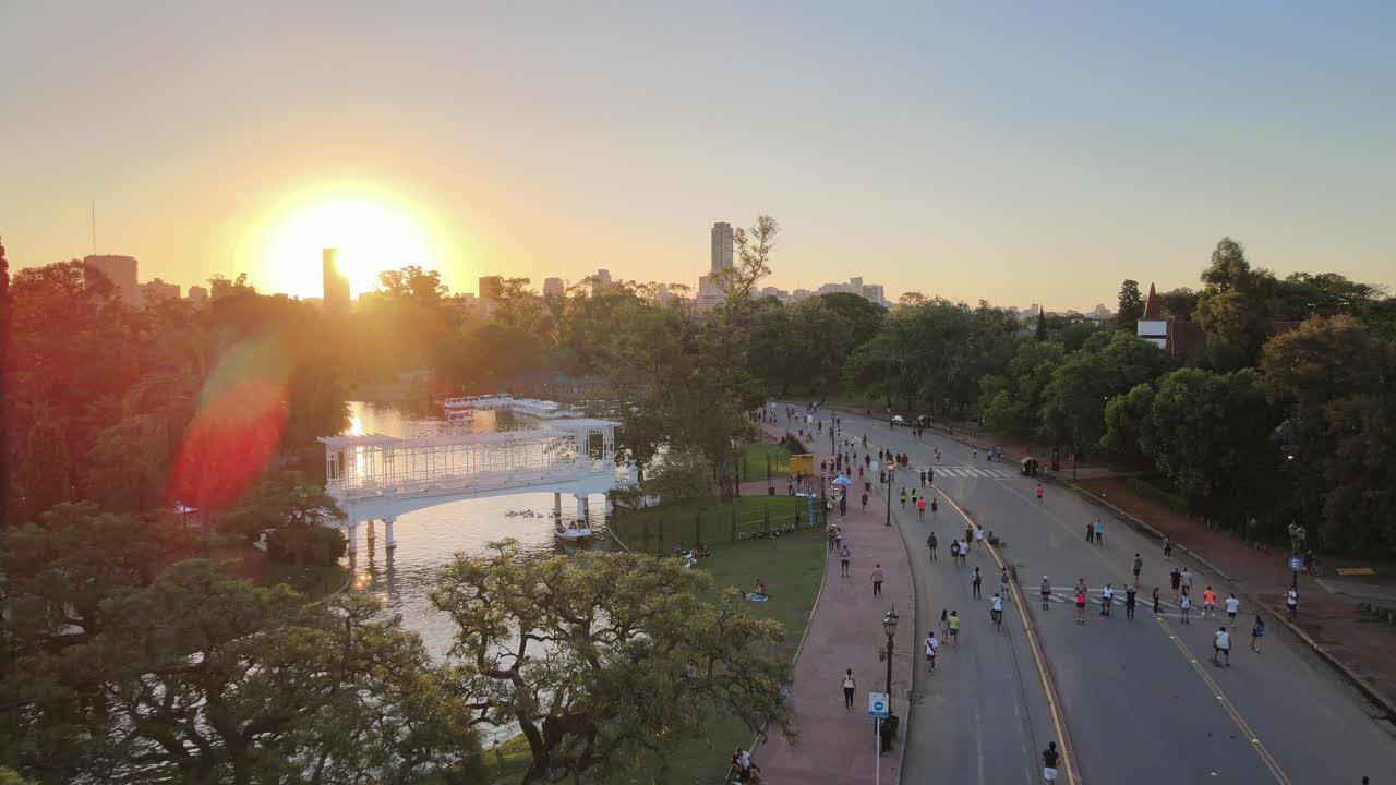 dolly aéreo de personas en la calle peatonal palermo woods cerca de rosedal gardens y estanque al atardecer, buenos aires
