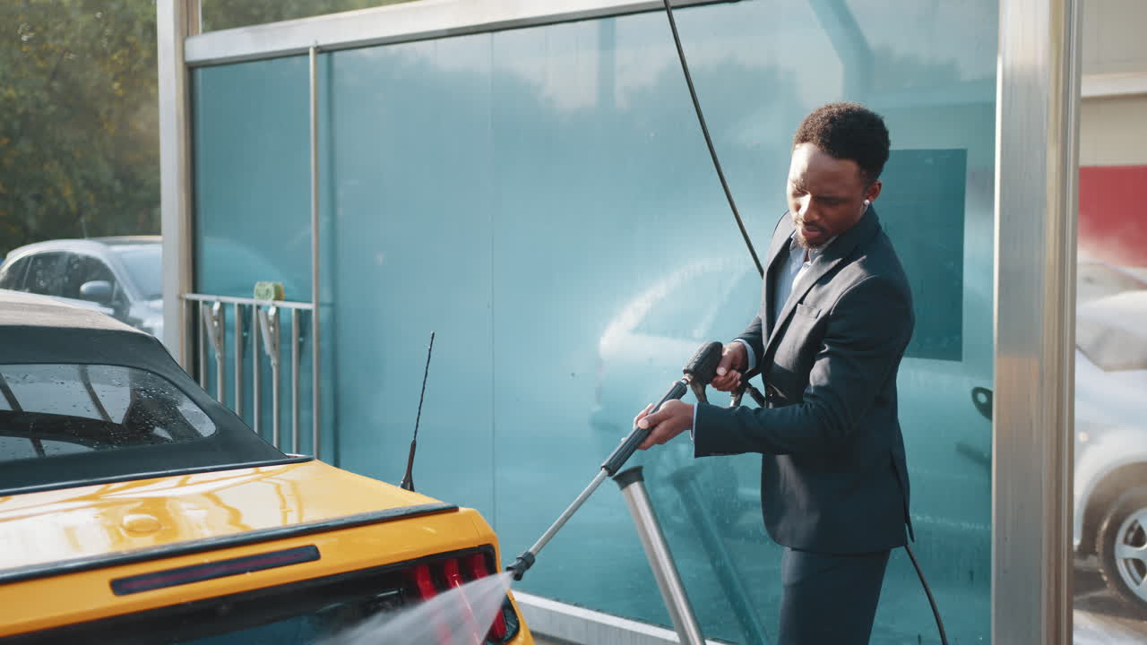 un hombre de negocios lavando un coche convertible amarillo en un lavado de coches