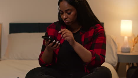 woman checking phone in bed at night