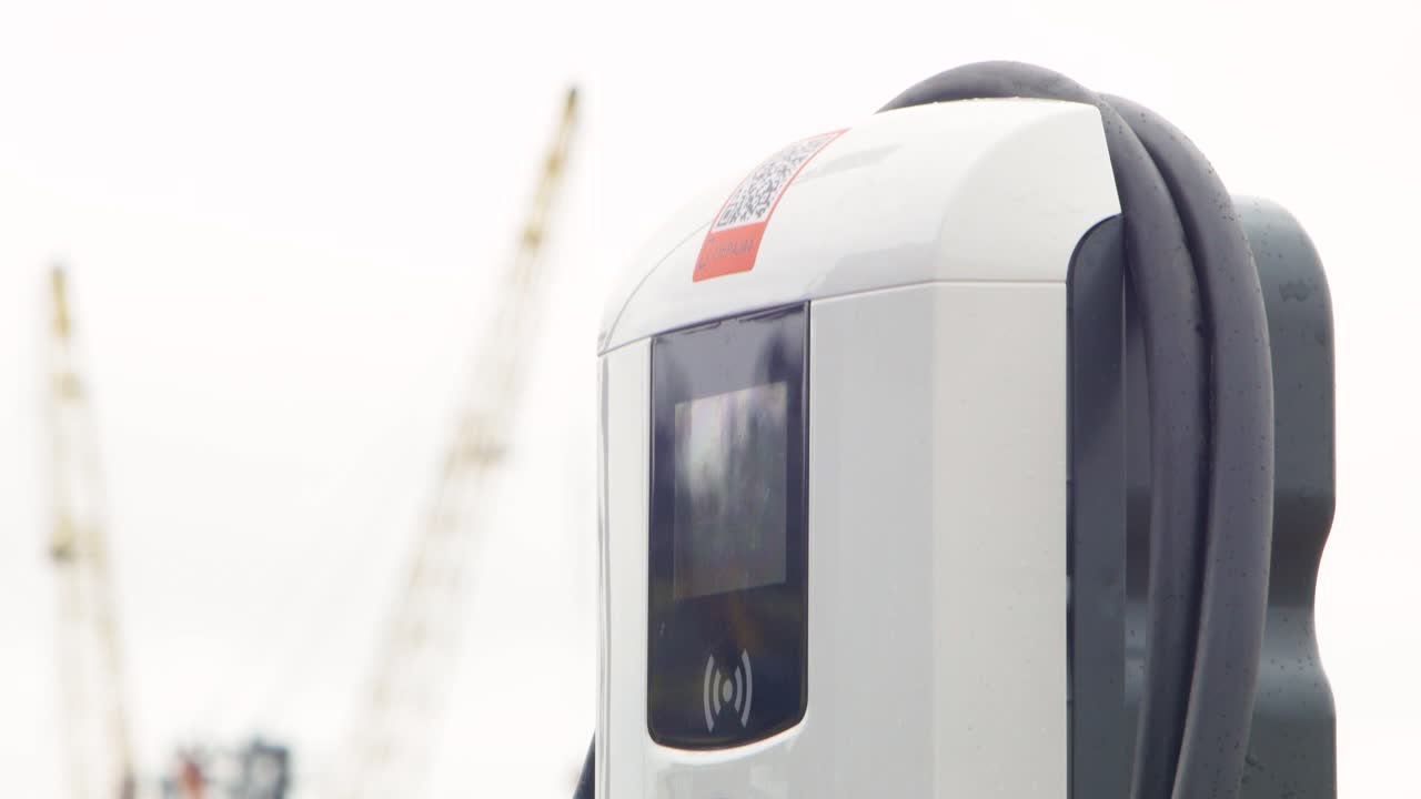 sistema de estación de carga de camiones eléctricos en una calle de la ciudad, un cable conectado a un camión, futuro del automóvil, energía limpia y sostenible, día nublado, toma de primer plano medio, inclinación de la cámara hacia arriba