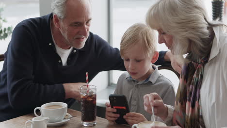 grandparents and child in cafe looking at phone