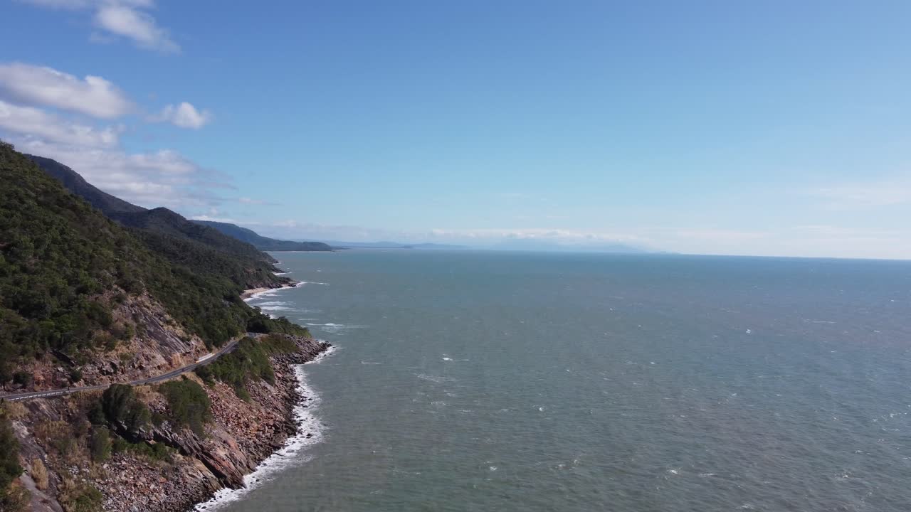 4K Drone shot of a rugged coastline with a coastal highway next to the Pacific Ocean in North Queensland, Australia
