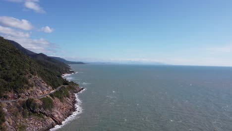4k drone shot of a rugged coastline with a coastal highway next to the pacific ocean in north queensland, australia