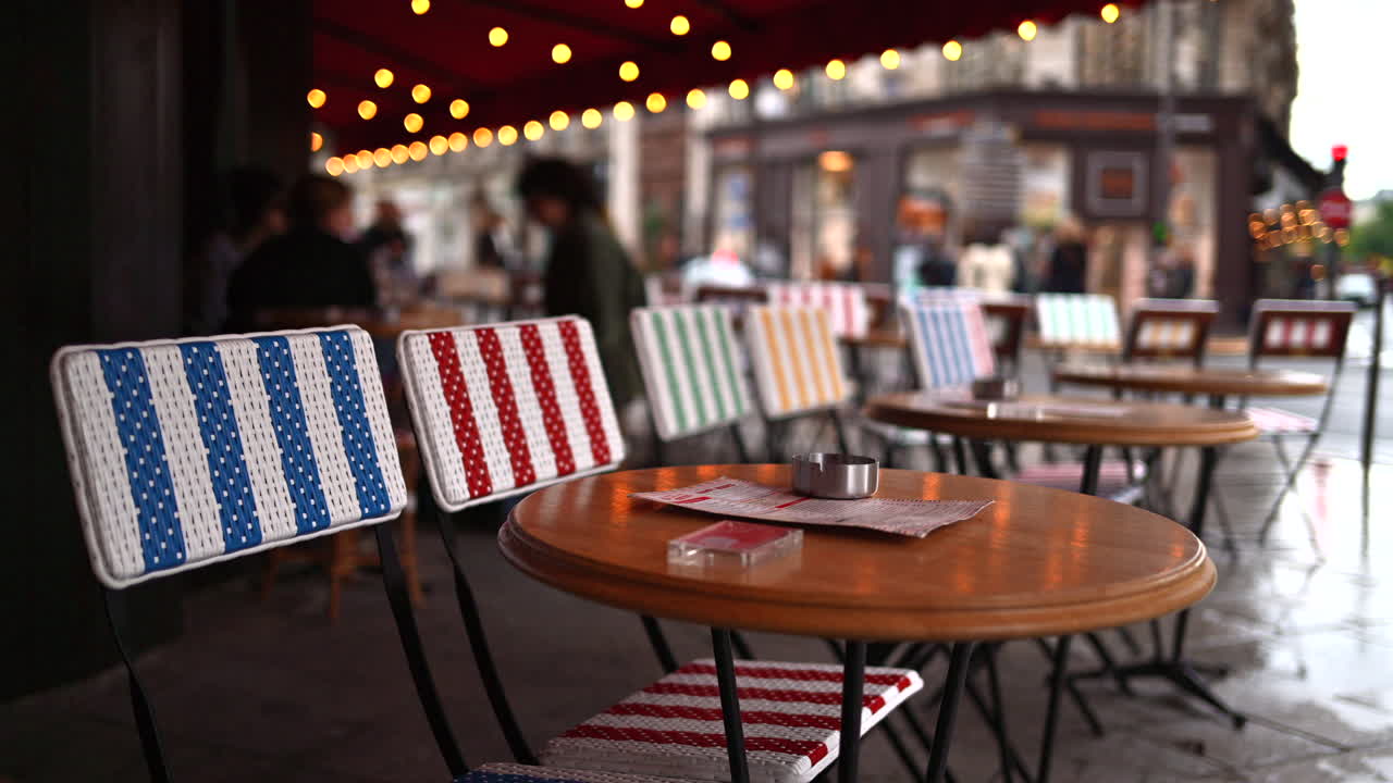Tables at a cafe with blurred people walking in the rain on the background