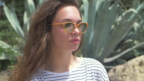 mujer joven con cabello largo y gafas de sol en un jardín