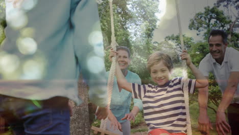 boy swinging on a swing being pushed by his parents