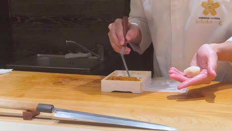 chef skillfully prepares uni nigiri sushi