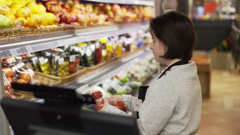 worker with down syndrome using a digital tablet in the fresh produce section to weight the goods