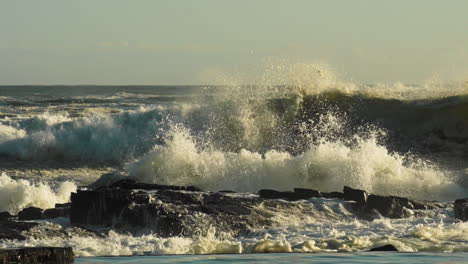 Olas-Del-Mar-Agitadas-Rompiendo-En-La-Costa-Rocosa-Creando-Enormes-Salpicaduras-Y-Espuma---Plano-Medio