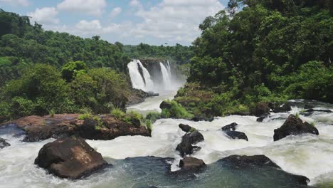 Cerca-De-Rocas-Oscuras-Cubiertas-Por-Hermosas-Aguas-Corrientes-En-Un-Paisaje-Escénico-De-Cascada,-Colorida-Y-Hermosa-Escena-De-Las-Cataratas-Del-Iguazú-Con-Una-Vista-Natural-Verde-Brillante-De-Los-árboles-De-La-Selva-Argentina