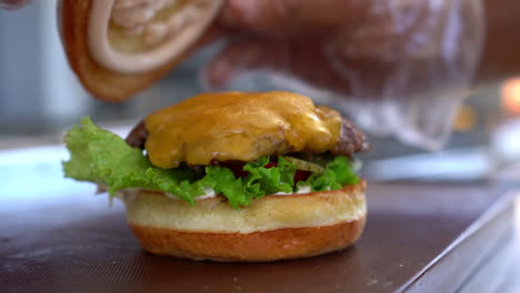 Ein-Brötchen-Auf-Einen-Cheeseburger-Legen---Nahaufnahme