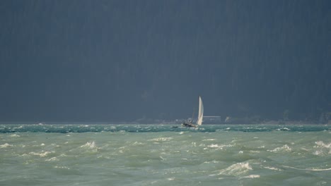 lonely sailboat at rough sea near alaskan coastline, slow motion wide view