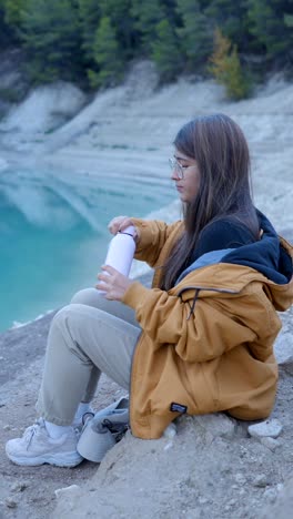woman hydrating by a scenic blue lake