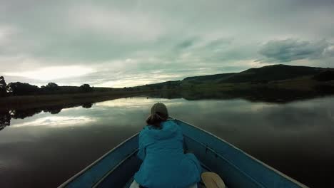 girl in the front of a moving boat on a beautiful lake in rainy weather