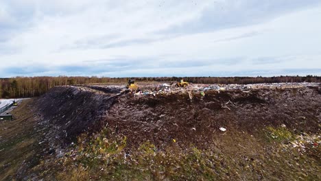 Aerial-flyover-landfill-full-of-trash,-pollution-environmental-problem,-garbage,-trucks-dump-waste-products-polluting-in-a-dump,-ascending-wide-angle-drone-shot-moving-forward