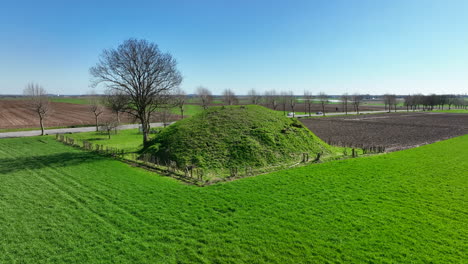 Aerial-circling-shot-of-Tumulus-of-Koninksem-on-sunny-day,-Tongeren,-Belgium