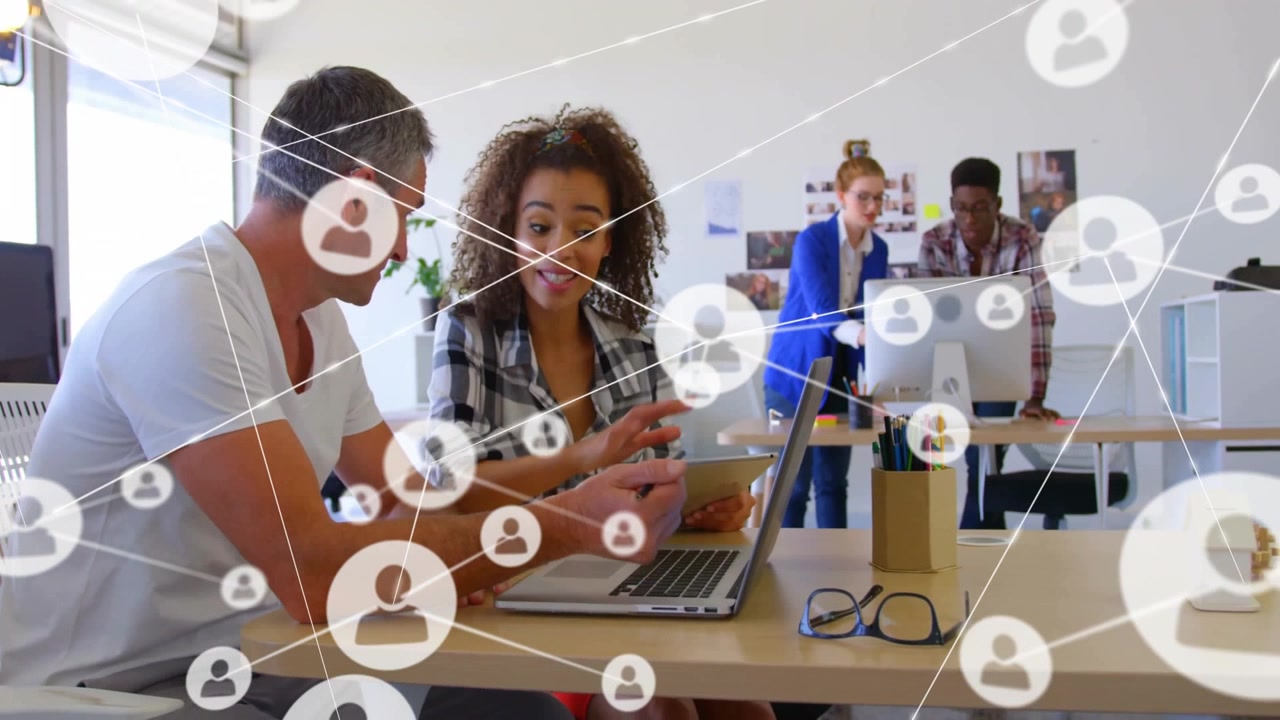 Team members discussing content on laptop and tablet in tech office, showing network icons