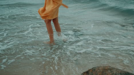 Woman in yellow dress standing in ocean waves