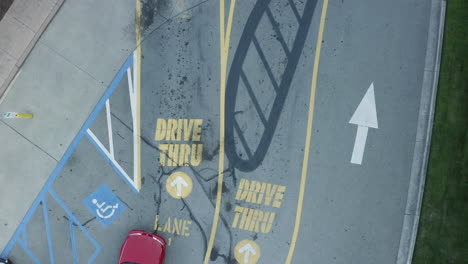 Overhead-drone-shot-of-red-car-entering-a-fast-food-restaurant-drive-thru-lane