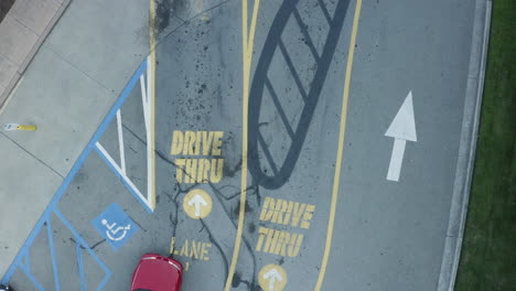 toma aérea de un auto rojo entrando en un restaurante de comida rápida a través del carril