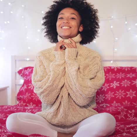 una joven sonriente y confiada sentada en su cama