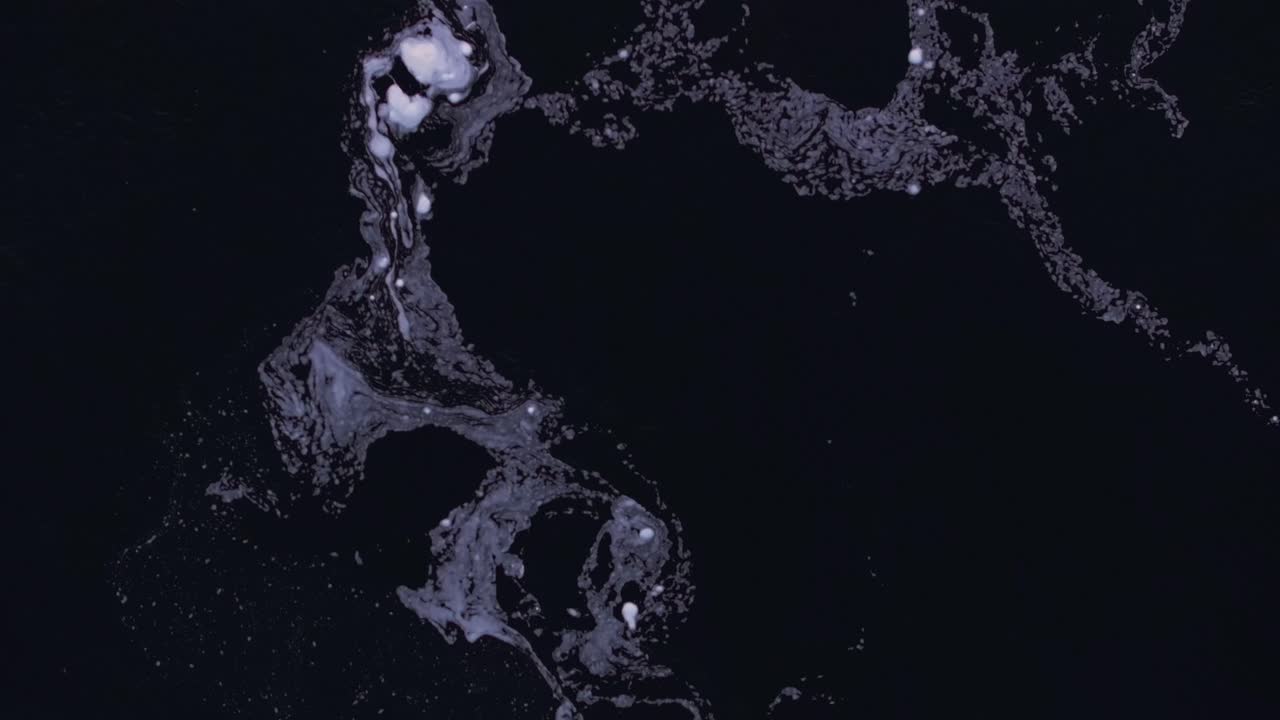 Top down view of foam swirling on the surface of a river showing the currents and eddies