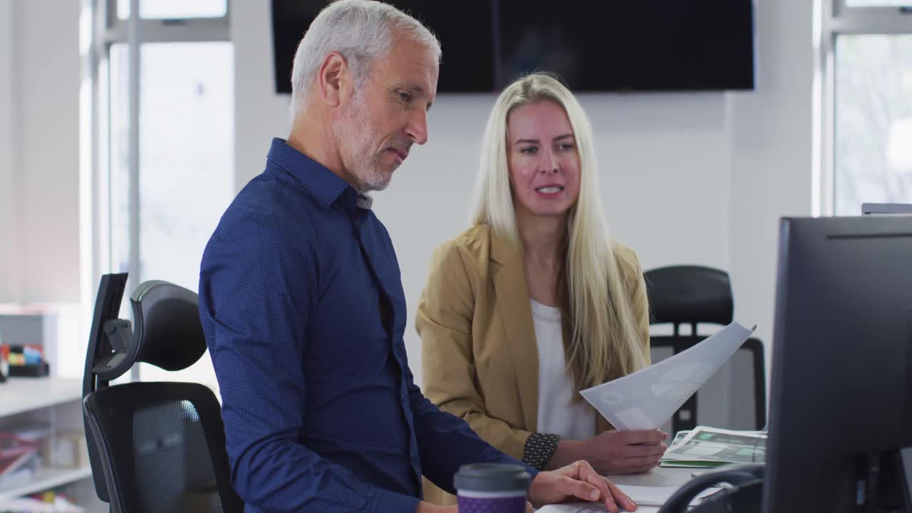 Man and woman discussing with each other while sitting on their desk at office