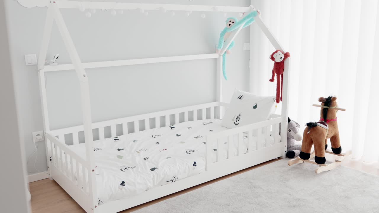 White toddler bed and rocking horse in cozy light filled children's room