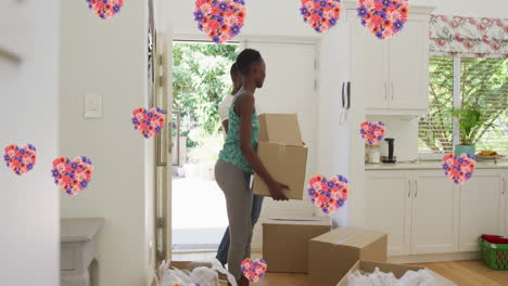 animation of heart icons with flowers over african american couple moving house