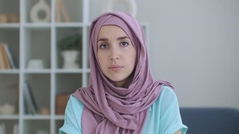 Una-Mujer-Con-Hijab-Mira-A-La-Cámara,-Asiente-En-Silencio-Con-La-Cabeza-Y-Escucha.-Conversación-A-Través-De-Un-Enlace-De-Vídeo.-Videoconferencia-Escucha-Las-Recomendaciones-Del-Médico.