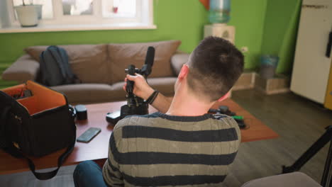 man setting up camera with microphone in home studio, adjusting equipment, preparing for filming, content creation in modern indoor setting