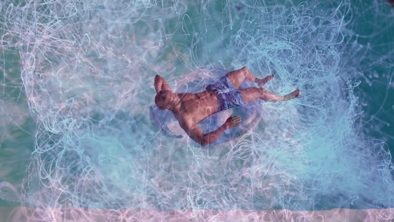 Mid adult man relaxing on inflatable tube, floating on calm water, displaying digital tech trails