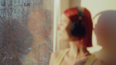 girl in headphones enjoying music with eyes closed on sunlit windowsill