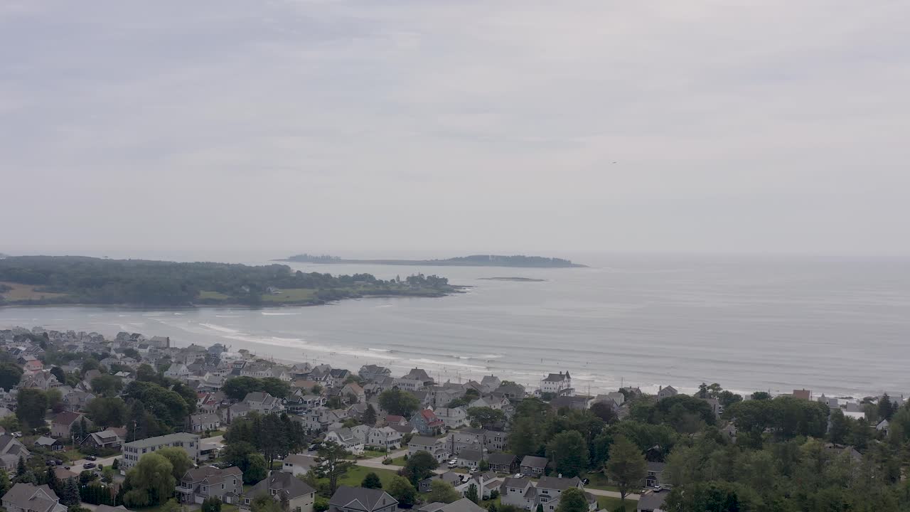 Vista de drone de comunidade de praia com pequeno avião Cessna decolando ao fundo enquanto pessoas estão na praia