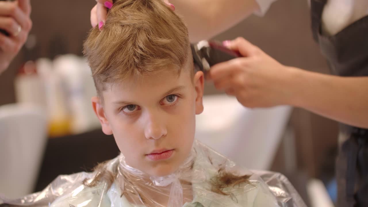 Primo piano di un bambino dai capelli chiari che si taglia i capelli con un tagliacapelli